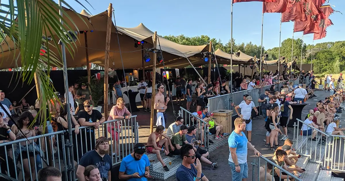 Visitors in the premium area at Defqon.1, with a bar under stretch tents